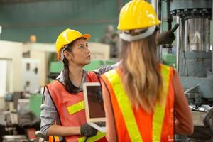 deux ouvrières travaillent sur le site de l'usine pour vérifier la machine dans la gamme de produits ou les produits sur le site. ingénieur ou technicien vérifiant le matériel ou la machine sur l'usine. industriel et usine. photo