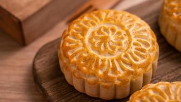 gâteau de lune fraîchement cuit de forme ronde - moonckae chinois pour le festival de la lune de la mi-automne sur fond de bois et plateau de service, gros plan, espace pour copie photo