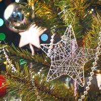 beau concept de décor de noël, babiole accrochée à l'arbre de noël avec une tache lumineuse étincelante, fond noir foncé flou, détail macro, gros plan. photo