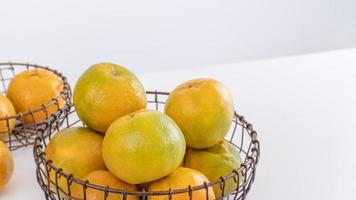 belles mandarines pelées dans une assiette et un panier en métal isolés sur une table blanche et propre dans un îlot de cuisine contemporain moderne, gros plan. photo