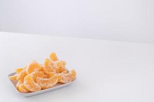 belles mandarines pelées dans une assiette et un panier en métal isolés sur une table blanche et propre dans un îlot de cuisine contemporain moderne, gros plan. photo