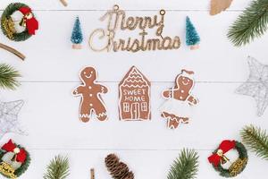 objets de décoration de composition de concept de noël, couronne de branche de sapin, biscuit de bonhomme en pain d'épice isolé sur une table en bois blanc, vue de dessus, pose à plat photo