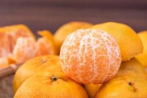 mandarine fraîche et belle de couleur orange sur un tamis en bambou sur une table en bois sombre. fruit traditionnel de saison du nouvel an lunaire chinois, gros plan. photo