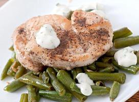 poitrine de poulet grillée avec haricots verts et sauce sur une plaque blanche. photo