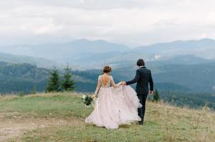 beau couple de mariage s'embrassant et s'embrassant près de la rive d'une rivière de montagne avec des pierres photo