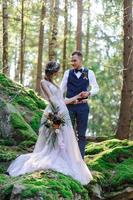 un beau couple de jeunes mariés, un moment heureux et joyeux. un homme et une femme se rasent et s'embrassent dans des vêtements de vacances. cérémonie de mariage de style bohème dans la forêt à l'air frais. photo