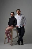 une femme enceinte et son mari s'embrassent sur un fond gris. couple attend un bébé. photo