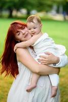 maman embrasse et joue avec sa fille d'un an enveloppée dans une serviette après le bain. photo