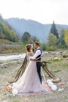 un beau couple de jeunes mariés, un moment heureux et joyeux. un homme et une femme se rasent et s'embrassent dans des vêtements de vacances. cérémonie de mariage de style bohème dans la forêt à l'air frais. photo