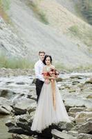 mariés. cérémonie de mariage près d'une rivière de montagne photo