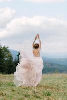 Whirling bride holding voile jupe de robe de mariée à forêt de pins photo