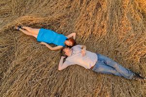 un agriculteur adulte et sa femme passent du temps dans les champs. l'homme est assis. une femme se tient à côté de lui et le serre dans ses bras. une femme embrasse son mari sur la tête. photo