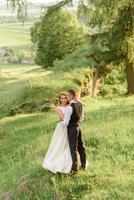 mariés dans un champ de blé. le couple s'embrasse au coucher du soleil photo