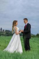 mariés dans un champ de blé. le couple s'embrasse au coucher du soleil photo