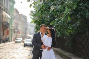 séance photo de mariage sur le fond de l'ancien bâtiment. le marié regarde sa mariée poser. photographie de mariage rustique ou bohème.