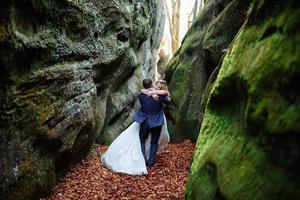 la mariée et le marié se tiennent au sommet d'une falaise. le coucher du soleil. photo