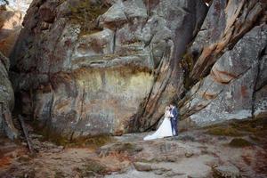 la mariée et le marié se tiennent au sommet d'une falaise. le coucher du soleil. photo