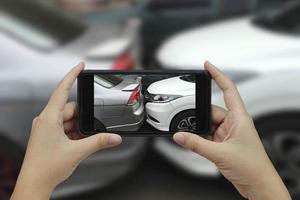 une main tenant un smartphone prend une photo sur les lieux d'un accident de voiture, d'un accident de voiture.