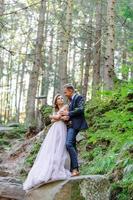 un beau couple de jeunes mariés, un moment heureux et joyeux. un homme et une femme se rasent et s'embrassent dans des vêtements de vacances. cérémonie de mariage de style bohème dans la forêt à l'air frais. photo