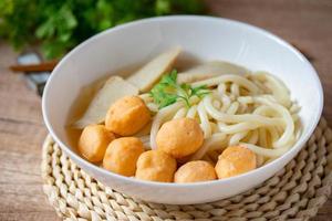 udon, boulettes de crevettes et boulettes de poisson dans une soupe claire cuisine japonaise dans une tasse en porcelaine blanche photo