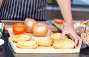 chef préparant la tomate d'oignon de pain et faisant l'hamburger dans la cuisine. photo