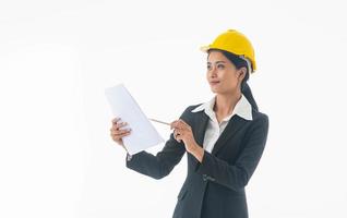 jeune ingénieur femme porte un costume noir et un casque de sécurité jaune tenant une note sur fond blanc isolé. photo