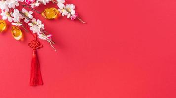 concept de design du nouvel an lunaire chinois - beau noeud chinois avec fleur de prunier isolé sur fond rouge, mise à plat, vue de dessus, mise en page aérienne. photo