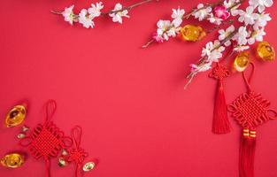 concept de design du nouvel an lunaire chinois - beau noeud chinois avec fleur de prunier isolé sur fond rouge, mise à plat, vue de dessus, mise en page aérienne. photo