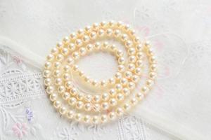 collier de perles sur fond de tissu blanc, gros plan de perles de verre photo