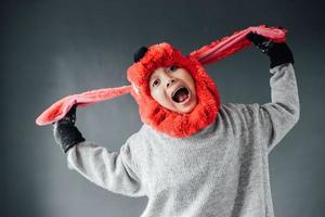 mignon garçon avec une expression heureuse portant des vêtements d'hiver se félicite de la saison d'hiver photo