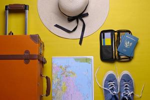 mise à plat de divers accessoires de voyage ou de vacances sur fond jaune photo