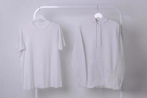 maquette d'un t-shirt basique blanc et d'un sweat à capuche suspendu à un portant à vêtements photo