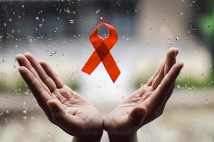 ruban rouge sur les mains pour le sida et le fond de la campagne contre le cancer photo