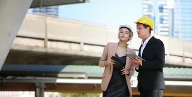 l'ingénieur et la femme d'affaires vérifient le presse-papiers sur le chantier de construction. le concept d'ingénierie, de construction, de vie urbaine et d'avenir. photo