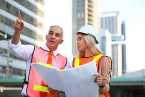 l'ingénieur et la femme d'affaires vérifient le presse-papiers sur le chantier de construction. le concept d'ingénierie, de construction, de vie urbaine et d'avenir. photo