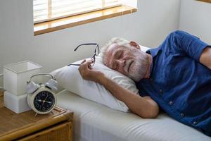 les cheveux gris masculins seniors dorment sur le lit. photo