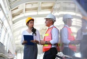 l'ingénieur et la femme d'affaires vérifient le presse-papiers sur le chantier de construction. le concept d'ingénierie, de construction, de vie urbaine et d'avenir. photo