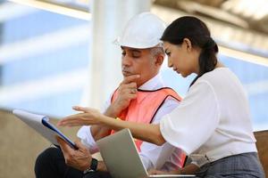 l'ingénieur et la femme d'affaires vérifient le presse-papiers sur le chantier de construction. le concept d'ingénierie, de construction, de vie urbaine et d'avenir. photo