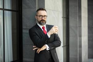 homme d'affaires hipster en costume debout avec une tasse de café près du bureau en plein air photo