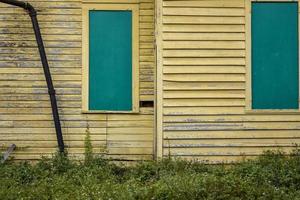 extérieur d'un bâtiment abandonné avec revêtement jaune et fenêtres bleu sarcelle photo