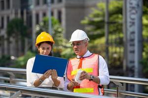 l'ingénieur et la femme d'affaires vérifient le presse-papiers sur le chantier de construction. le concept d'ingénierie, de construction, de vie urbaine et d'avenir. photo