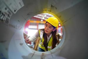 une ouvrière contremaître ou ouvrière travaille sur le site de l'usine pour vérifier la machine ou les produits sur le site. ingénieur ou technicien vérifiant le matériel ou la machine sur l'usine. industriel et usine. photo