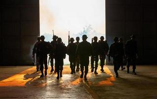 silhouettes de soldats de l'armée dans le brouillard contre un coucher de soleil, équipe de marines en action, feu et fumée entourés, tir avec fusil d'assaut et mitrailleuse, attaque ennemie photo