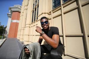 homme afro-américain s'amusant à marcher dans le centre-ville - jeune homme heureux profitant d'un coucher de soleil en plein air - mode de vie de la génération du millénaire et concept d'attitude positive des personnes photo