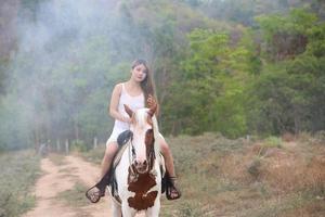 jeune femme avec son cheval dans la lumière du coucher du soleil du soir. photographie en plein air avec une fille mannequin. mode de vie photo