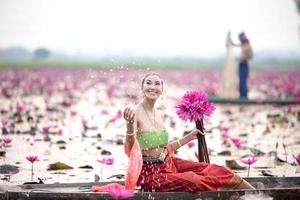 jeunes femmes asiatiques en costume traditionnel dans le bateau et fleurs de lotus roses dans l'étang. belles filles en costume traditionnel. fille thaïlandaise en robe thaïlandaise rétro, fille thaïlandaise en costume traditionnel photo