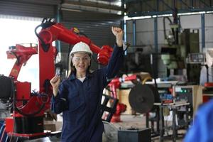 divers ingénieurs et travailleurs multiculturels de l'industrie lourde dans un bras de robot automatique à contrôle uniforme pour l'utilisation en usine. l'entrepreneur industriel féminin utilise une tablette.