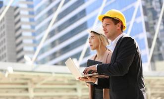 l'ingénieur et la femme d'affaires vérifient le presse-papiers sur le chantier de construction. le concept d'ingénierie, de construction, de vie urbaine et d'avenir. photo