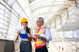 l'ingénieur et la femme d'affaires vérifient le presse-papiers sur le chantier de construction. le concept d'ingénierie, de construction, de vie urbaine et d'avenir. photo