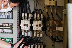 ingénieur électricien testeur de travail mesurant la tension et le courant de la ligne électrique dans le contrôle de l'armoire électrique. photo